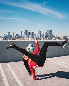 a woman kicking a soccer ball in the air with her legs stretched out and feet spread wide