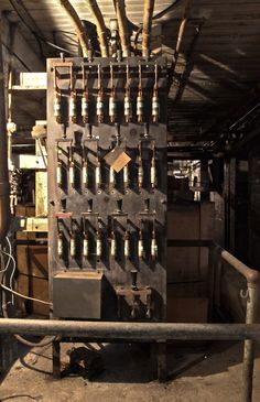 an old machine with lots of tools on it's back wall in a building