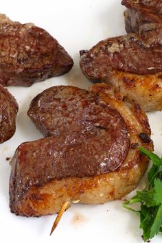 some meat is on a white plate with green garnish