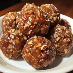 a white plate topped with nuts and chocolate covered balls on top of a wooden table