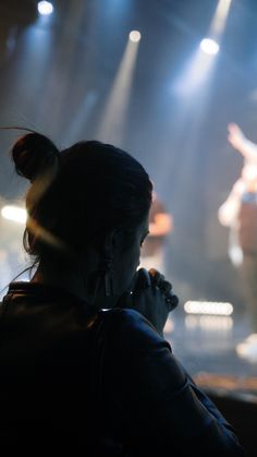 a woman standing in front of a stage while talking on a cell phone to someone else