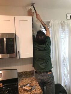 a man is working on the ceiling in his kitchen