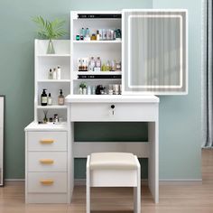 a white dressing table with drawers and a mirror above it, in front of a blue wall