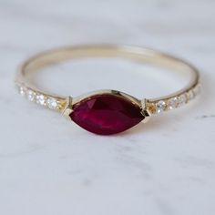 an oval shaped ruby and diamond ring on a marble surface