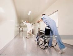 a man in a wheel chair is pushing another man into the hospital corridor with his leg up