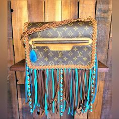 a brown and blue purse with fringes hanging from it's front pocket on a wooden shelf