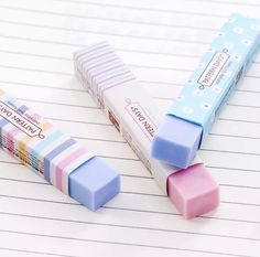 three erasers sitting next to each other on lined paper