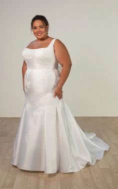 a woman in a white wedding dress standing on a wooden floor with her hands on her hips