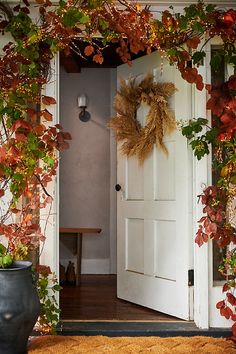 an open door with a wreath hanging on the front and side of it next to a potted plant