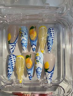 Description: Add a touch of elegance and freshness to your nails with our Long Stiletto Lemon and Chinoiserie Press On Nails. This handmade set features a stunning design with bright yellow lemons and intricate blue floral Chinoiserie patterns. Perfect for those who love a sophisticated and stylish look, these nails will make a beautiful statement. Features: Elegant Design: Long stiletto nails with a yellow base featuring vibrant lemon designs an Orange Seashell Nails, Bold Blue Nails, Hand Painted Acrylic Nails, Lemon Inspired Nails, Lemon And Blue Nails, Light Blue And Gold Nails, Stiletto Nails Blue, Nails For Italy, Lemon Nails Designs