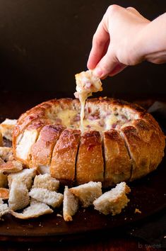 someone is dipping cheese on top of a baked bread bun with croutons and parmesan