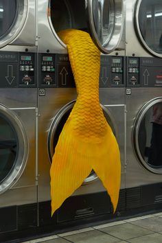 a yellow fish sculpture hanging from the side of a washer in a public laundment