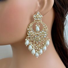 a close up of a woman's ear wearing earrings with pearls and beads on it