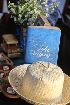 a hat and book sitting on top of a table next to other items with flowers in the background