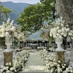 an outdoor ceremony setup with white flowers and greenery on the aisle, overlooking water