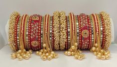 Traditional Punjabi Style Hanging Pearls Chura Set. Decorated With Beautiful Pearls Bunches Bangles At Both End Of Chura. Center Piece Is Prettified With Exclusive Rajwadi Style Hand Painting and Glass Kundan Beading On it. Hanging Pearls Chain At Both Side Of This Chura Is Making This Ensemble More Traditional Yet Elegant. A Glorious Masterpiece To Make You Look Glowy On Any Celebration. This is a set of 34 Bangles (17 For Each Hand). Ceremonial Bridal Sets With Latkans For Festivals, Festive Ceremonial Bridal Sets With Latkans, Traditional Bridal Sets With Zari Work, Bollywood Bridal Accessories For Marriage, Traditional Bridal Sets For Marriage, Red Wedding Traditional Wear With Latkans, Traditional Bridal Accessories For Festive Season, Festive Bridal Accessories With Tilla For Marriage, Bridal Sets With Tilla For Wedding And Festivals