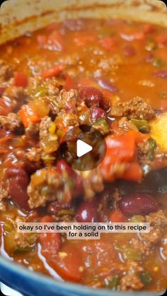 a pot filled with meat and vegetables being stirred by a wooden spoon to stir it