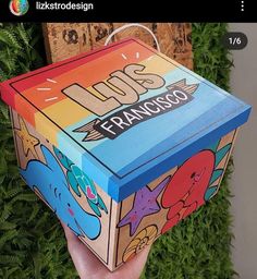 someone is holding up a colorful box in front of some green plants and grass with the words los francisco written on it