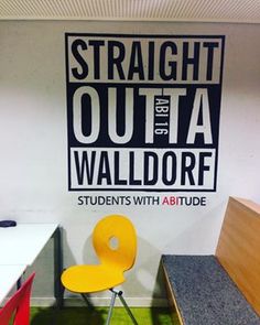 an office cubicle with a chair and desk in front of a sign that says straight out the wall