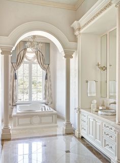 an elegant bathroom with marble floors and columns, chandelier above the jacuzzi tub