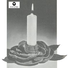 a white candle with a knitted scarf around it