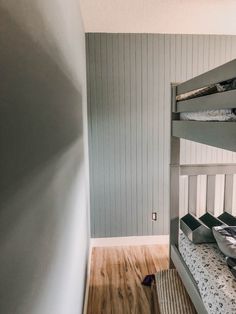 a bunk bed sitting in the corner of a room next to a wooden floor and wall