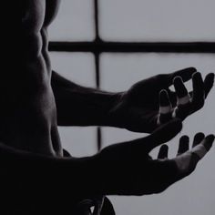 black and white photograph of man doing yoga with his hands in the air while looking out window