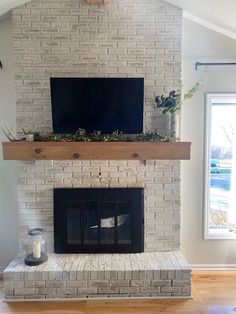 a fireplace with a flat screen tv mounted above it and plants on the mantel