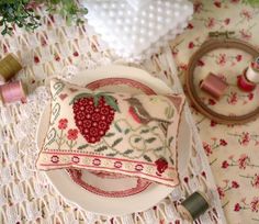 a white plate topped with a pillow on top of a table next to spools of thread