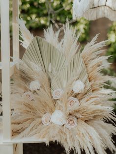 an arrangement of flowers and feathers is displayed on the back of a chair in a garden