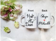 two coffee mugs sitting next to each other on a table with flowers in the background