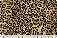 an animal print fabric with brown and black spots on the front, along with a ruler