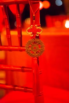 a red chair with a tassel hanging from it's back and a gold medallion attached to the seat