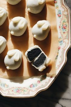 there are many small desserts on the plate with white frosting and black icing