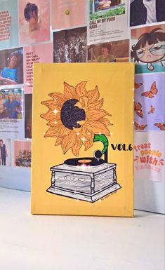 a sunflower is sitting on top of a record player in front of a wall full of pictures