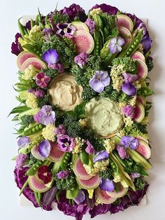 an arrangement of flowers and vegetables arranged in the shape of a circle with dip on top