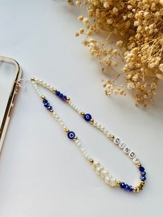 two bracelets with pearls and blue beads on a table next to a cell phone