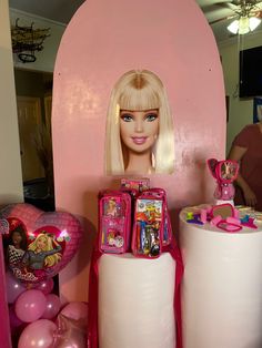 there is a barbie doll on top of two large cylindrical cylinders in front of balloons