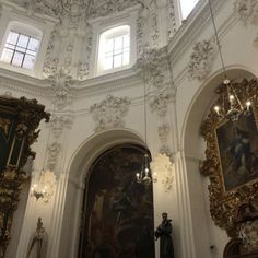 the interior of a church with paintings and chandeliers hanging from it's ceiling