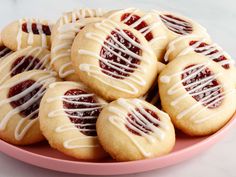 a pink plate filled with cookies covered in white icing and drizzled