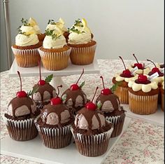 several cupcakes with cherries and chocolate frosting on a white platter