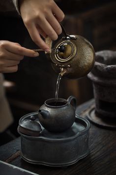 a person pouring water into a tea pot