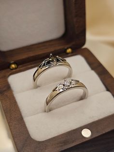 two wedding rings in a wooden box with white furnishing and gold accents on display