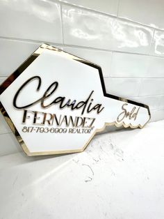 a white and gold sign that says claudia fernand realtor on the side of a wall