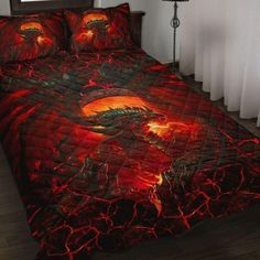 a bed covered in red and black bedspread with dragon artwork on the comforter