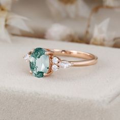 an oval cut green and white stone ring with three diamonds on it's sides