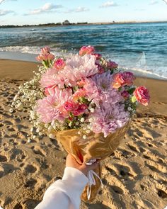 a person holding a bouquet of flowers on the beach