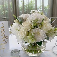 a vase filled with white flowers sitting on top of a table next to a card