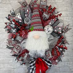 a christmas wreath with a gnome face and red, white and black ribbons on it