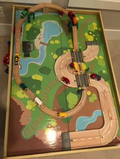 a toy train set on top of a wooden table with cars and trucks around it